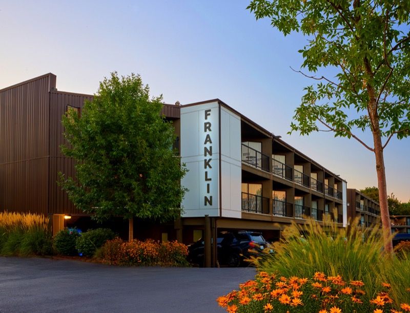 Exterior of the Franklin building at sunset, corrugated metal facade, balconies, and landscaping
