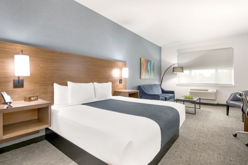 Deluxe King guest room with king bed, blue sofa, abstract art, and desk area